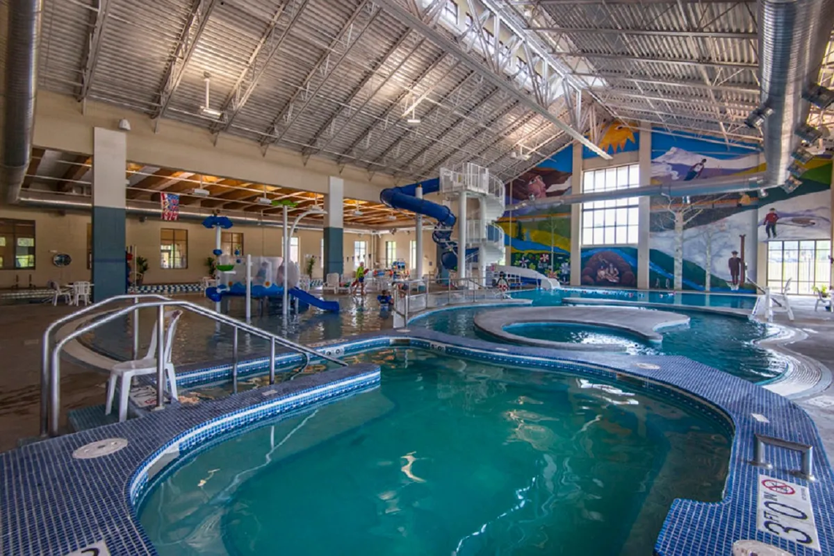 This interior image showcases the lively Grand Park Rec Center, with children playing on water slides and vibrant, colorful murals creating a joyful, family-friendly environment focused on recreation and fun.