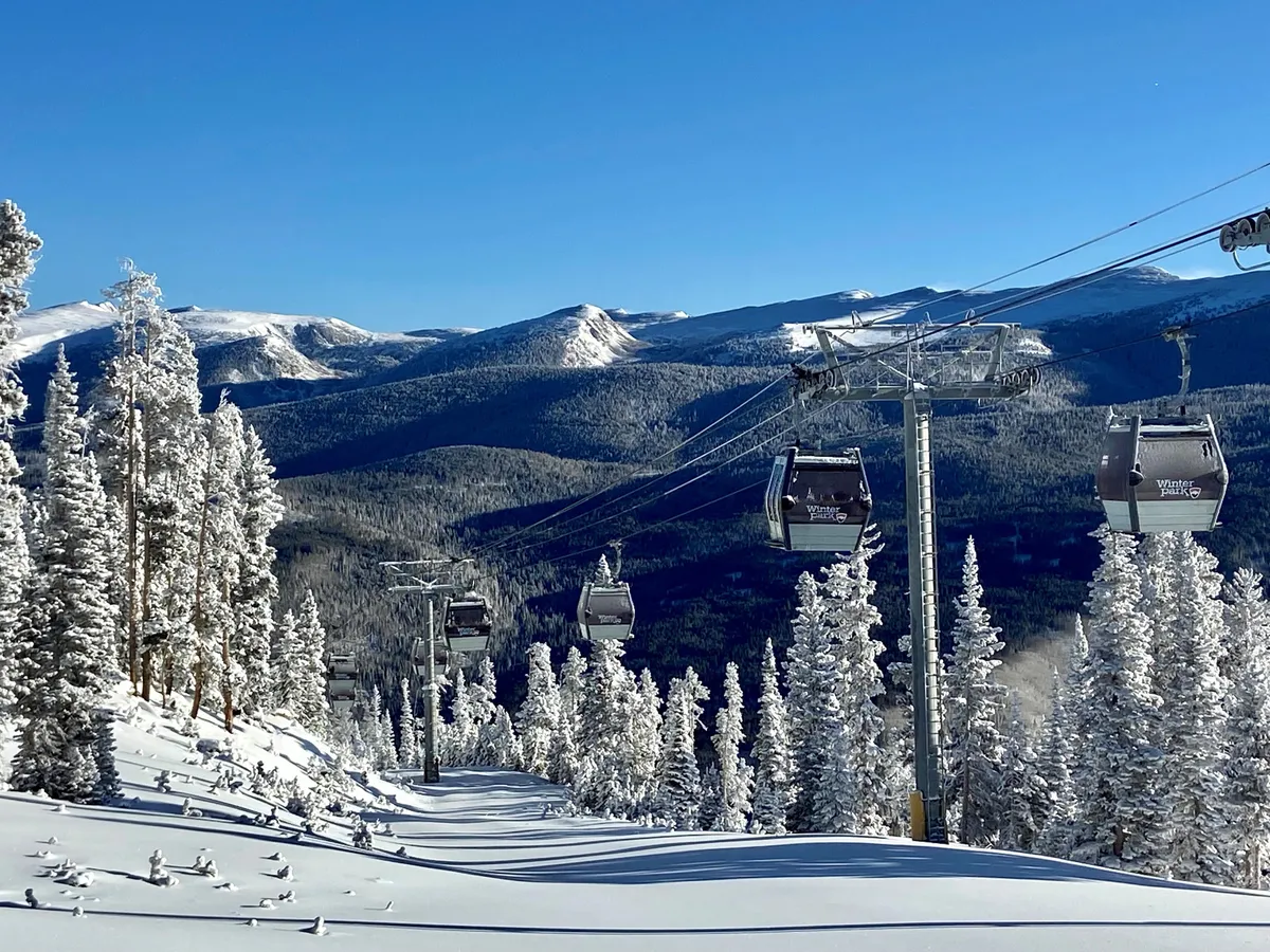 A scenic gondola lift glides above snow-covered trees with a dramatic mountain backdrop, capturing the essence of adventure and the exhilarating spirit of mountain exploration.
